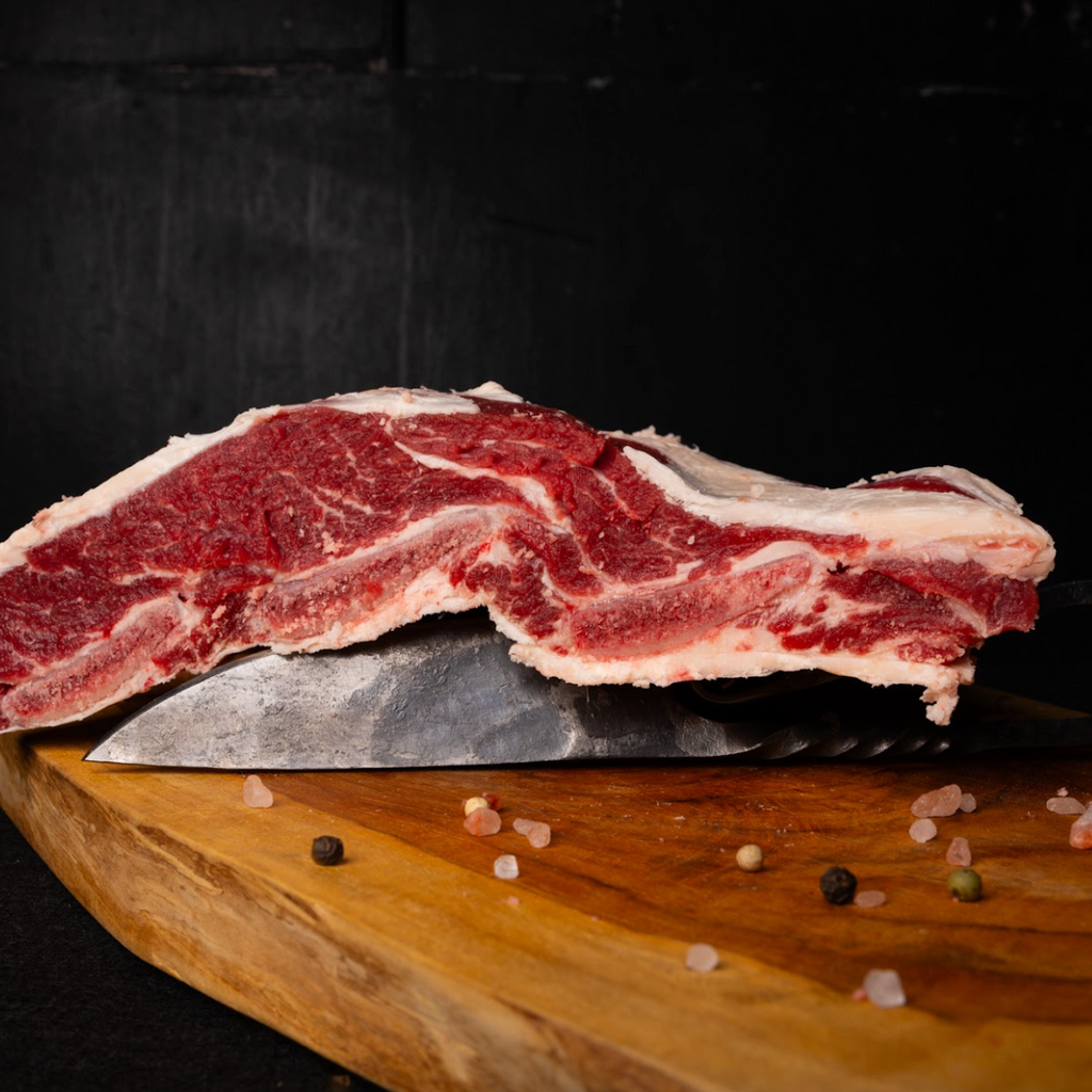 Raw steak on a wooden cutting board with a knife, black background