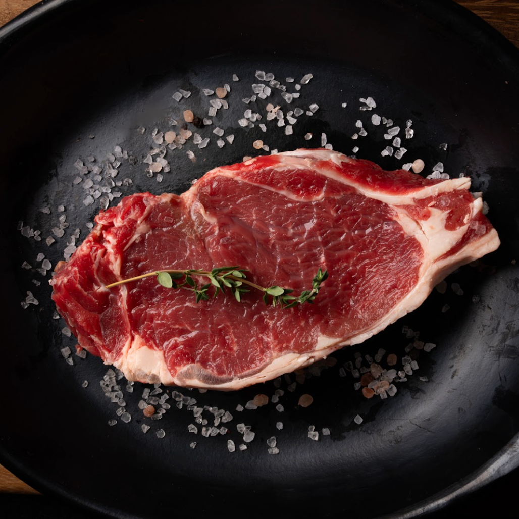 Raw steak on a black plate with salt and thyme