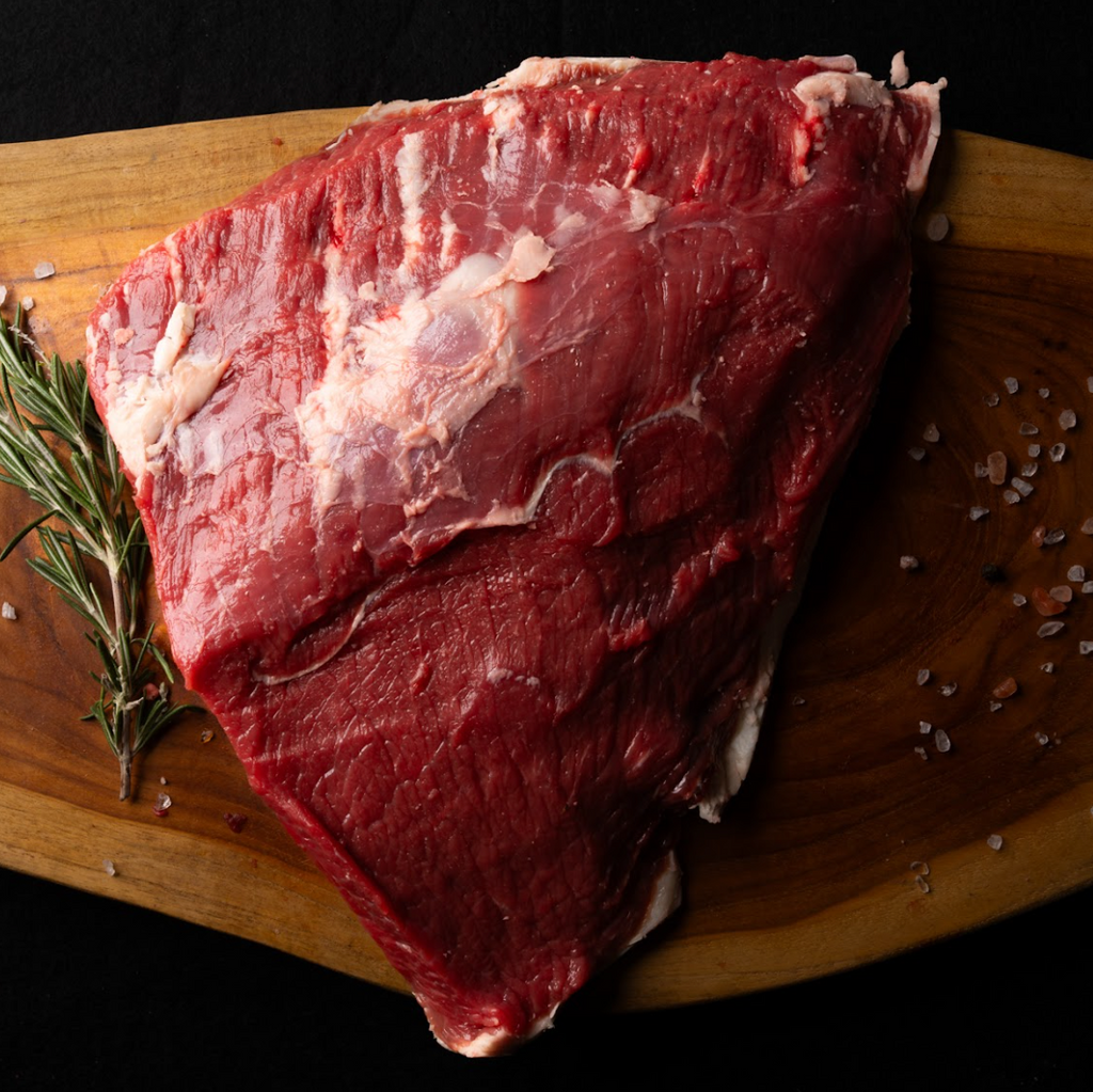 Raw beef on a wooden cutting board with rosemary and salt.