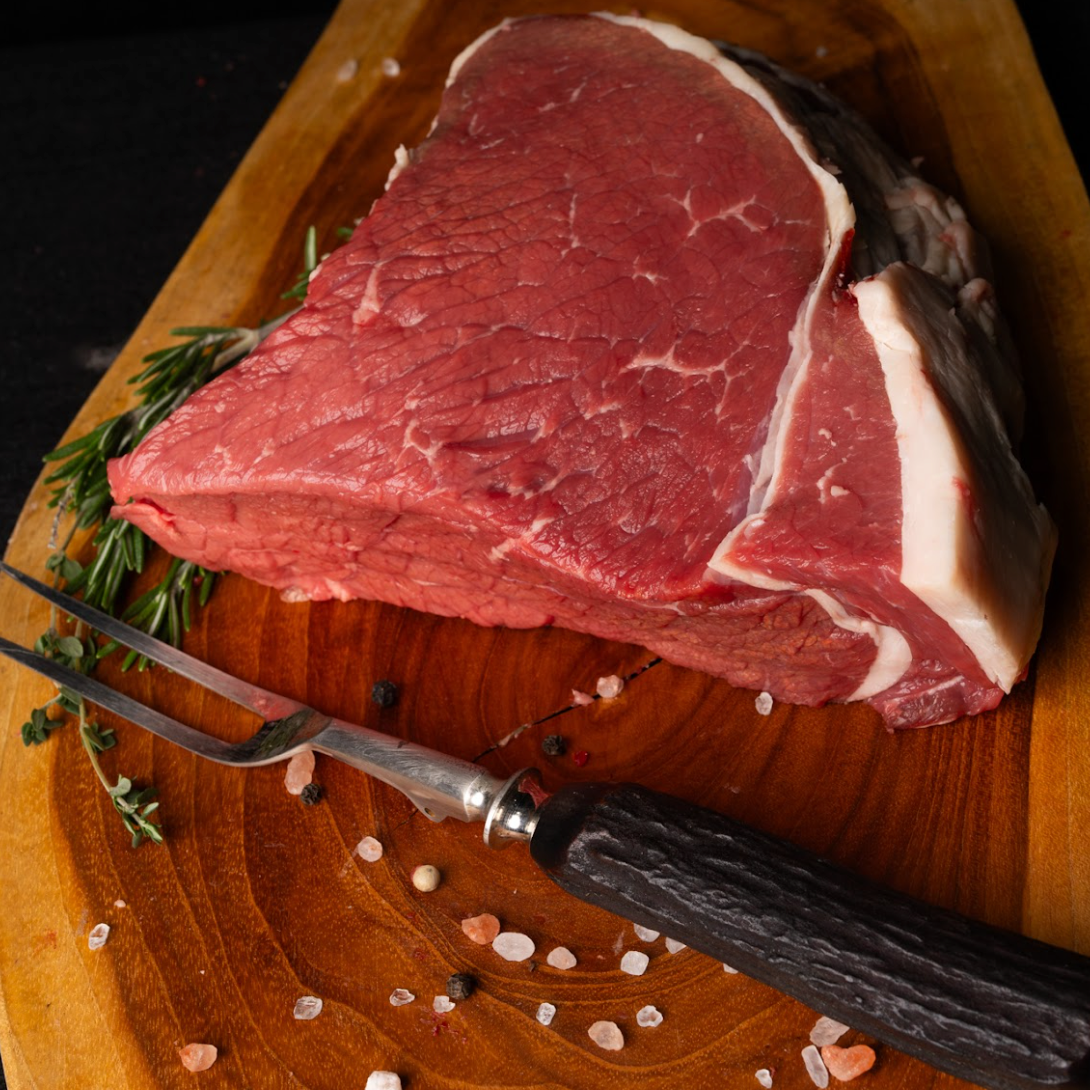 Raw steak on a wooden cutting board with a fork and knife