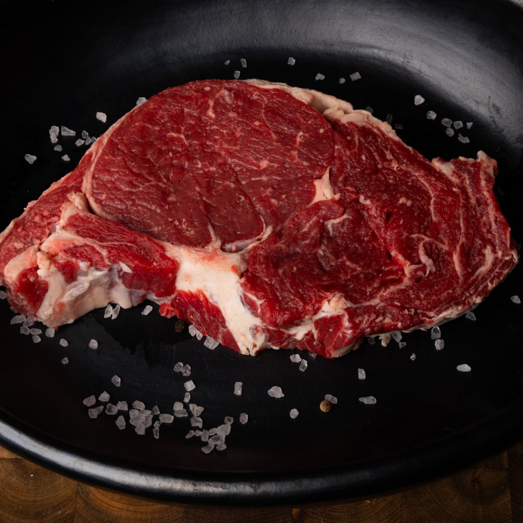 Raw steak on a black plate with salt crystals