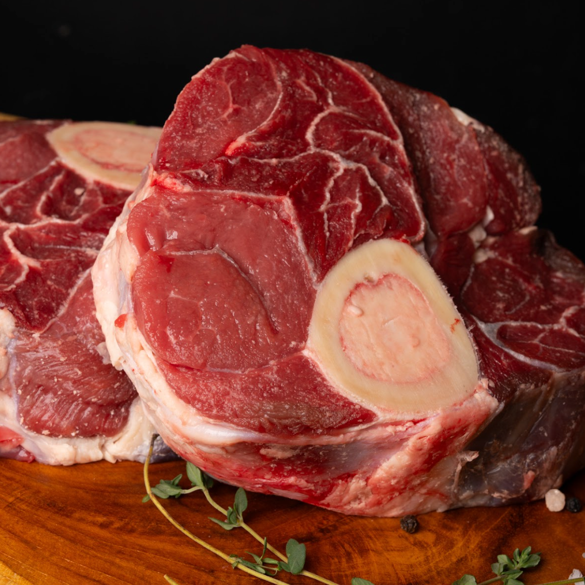 Two pieces of raw beef on a wooden cutting board with a dark background